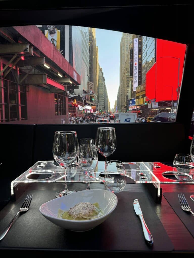 Dinner table set with pasta and wine glasses, looking out at Times Square